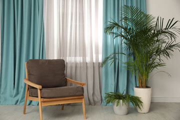 Comfortable armchair near window with elegant curtains in room