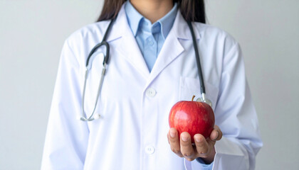 A doctor holding a fresh apple in the hands with the statement that one apple a day keeps the doctor away