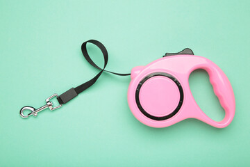 Pink plastic durable and ergonomic leash roulette for pets on mint background. Convenient...