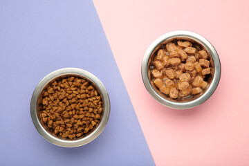 Wet and dry food for dogs and cats in silver bowl on pink background.