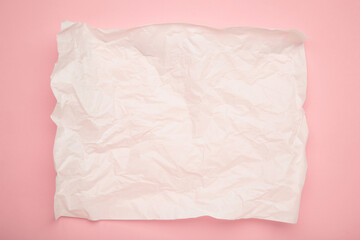 Obraz premium Crumpled piece of white parchment or baking paper on pink background. Copy space for text and design element.