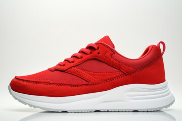 Red athletic sneaker side view on white background, casual modern running shoe with mesh and suede details and white sole