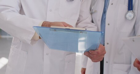 Doctors meet, exchange handshakes, and share research data. Coworkers show each other clipboards, look at test results, read medical reports. Cropped shot, shaking hands closeup. Teamwork concept - Powered by Adobe