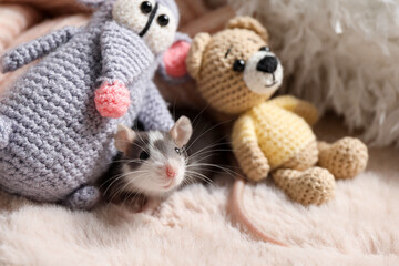 Fototapeta premium Adorable little rat and crocheted toys on faux fur