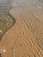 Close up of textuted beach sand and transparent ocean water