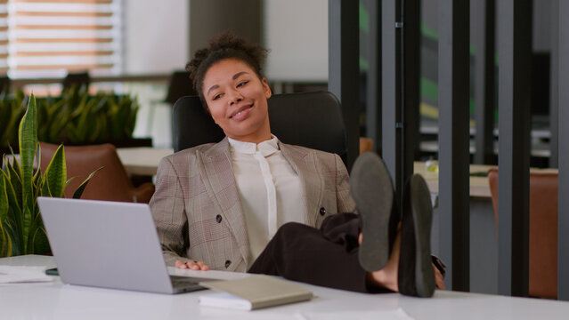 African American woman business employer ethnic satisfied smiling businesswoman typing accomplish online work laptop relaxation put legs on office desk relax rest comfort happy female girl enjoy break