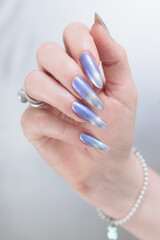 Female hand with long nails and bright light blue and silver manicure