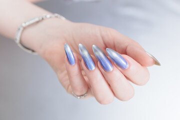 Female hand with long nails and bright light blue and silver manicure