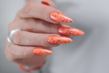 Woman hand with long nails and light orange coral neon manicure 