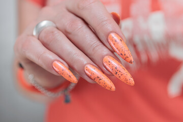 Woman hand with long nails and light orange coral neon manicure 