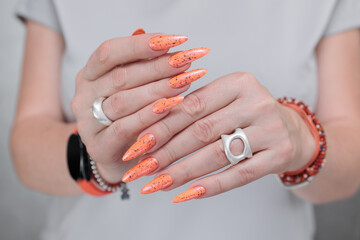 Woman hand with long nails and light orange coral neon manicure 