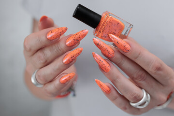 Woman hand with long nails and light orange red neon manicure