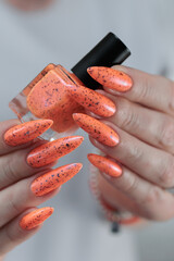 Woman hand with long nails and light orange neon manicure