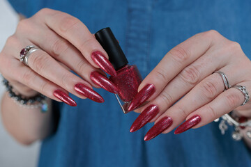 Obraz premium Female hand with long nails and a bright red manicure