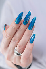 Woman's beautiful hand with long nails and bright blue manicure