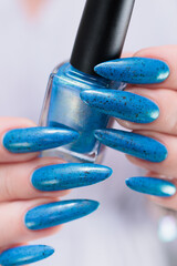 Woman's beautiful hand with long nails and bright blue manicure