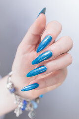 Woman's beautiful hand with long nails and bright blue manicure