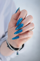 Woman's beautiful hand with long nails and bright blue manicure