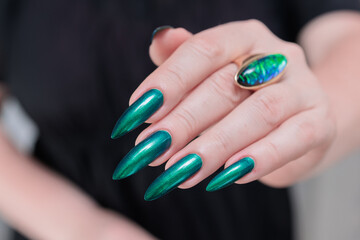 Woman's hand with long nails and green blue nail polish
