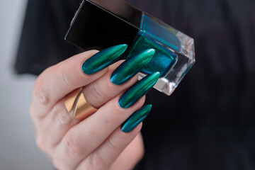 Woman's hand with long nails and green blue nail polish