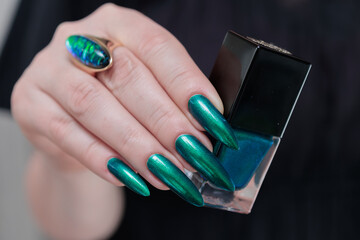 Woman's hand with long nails and green blue nail polish