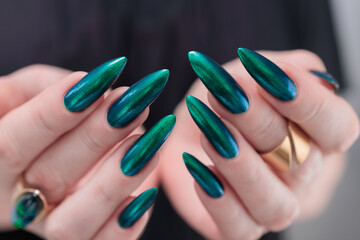 Woman's hand with long nails and green blue nail polish