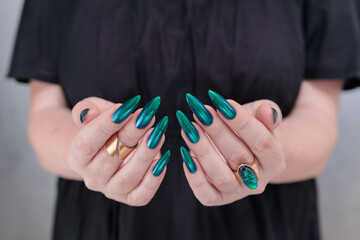 Woman's hand with long nails and green blue nail polish