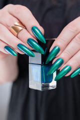 Woman's hand with long nails and green blue nail polish