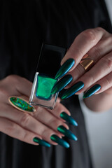 Woman's hand with long nails and green blue nail polish
