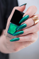 Woman's hand with long nails and green blue nail polish