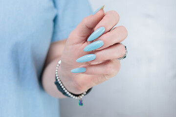 Woman's beautiful hand with long nails and light baby blue manicure