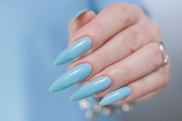 Woman's beautiful hand with long nails and light baby blue manicure