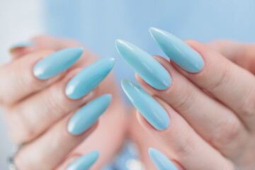 Woman's beautiful hand with long nails and light baby blue manicure