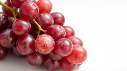 Fototapeta premium Single bunch of ripe, red grapes resting on a white surface, with every grape in sharp focus. The image showcases their natural texture and glossy appearance with no blur.