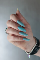 Woman's beautiful hand with long nails and light baby blue manicure