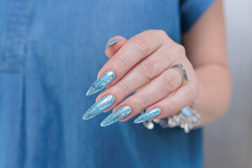 Female hand with long nails and bright light blue and silver manicure