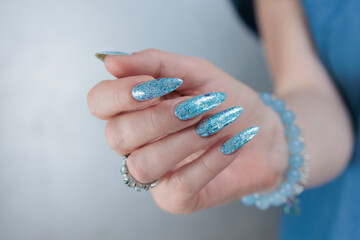 Female hand with long nails and bright light blue and silver manicure