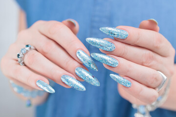 Female hand with long nails and bright light blue and silver manicure