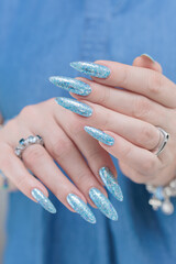 Female hand with long nails and bright light blue and silver manicure