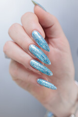 Female hand with long nails and bright light blue and silver manicure