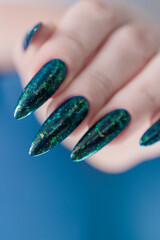Woman's hand with long nails and black green nail polish