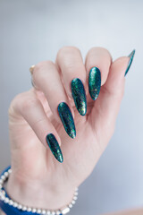 Woman's hand with long nails and black green nail polish