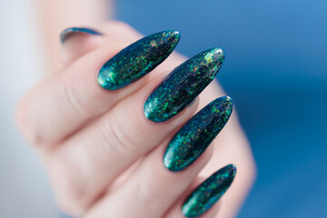 Woman's hand with long nails and black green nail polish
