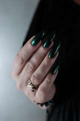 Woman's hand with long nails and black green nail polish