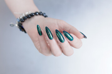 Woman's hand with long nails and black green nail polish