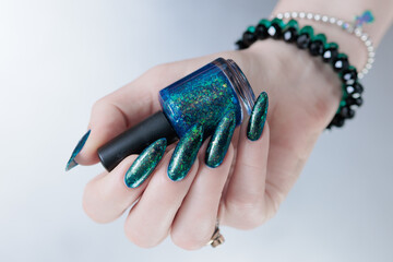 Woman's hand with long nails and black green nail polish
