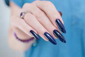 Woman's hand with long nails and black green nail polish