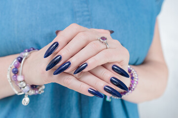 Woman's beautiful hand with long nails and dark blue manicure