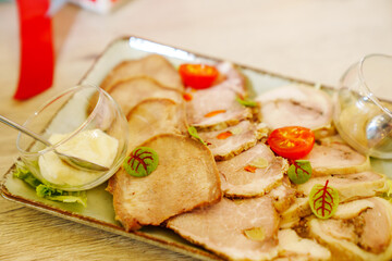 Cold cuts on a plate with sauces and cherry tomatoes and lettuce.
