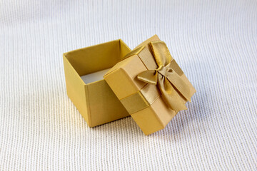Opened red gift box with silk golden ribbon bow on white knitted background